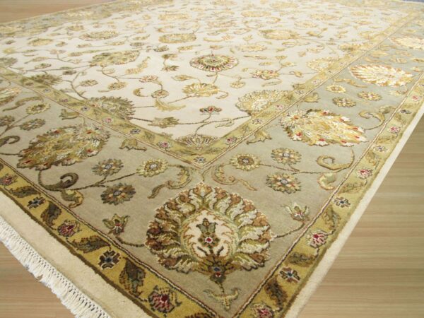 Traditional floral rug in cream and muted green with gold accents resting on light wood flooring.