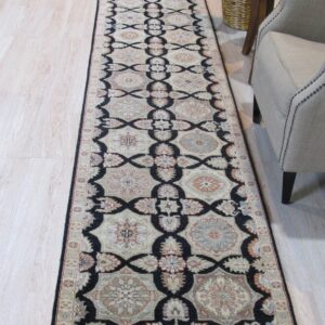 Black, cream, and muted multicolored runner rug on light flooring beside a beige chair.