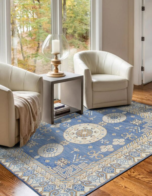 Blue, tan, and cream geometric rug grounding two white chairs on a hardwood floor near a window.