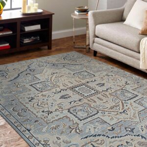 Geometric blue and brown traditional area rug on wood flooring next to a tan upholstered sofa.