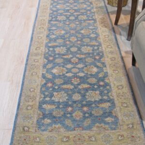 Traditional runner rug featuring a blue field and gold floral border rests on light wood flooring.