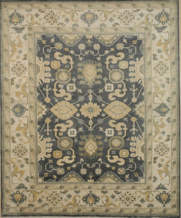 A traditional rug with a dark gray field and wide cream border featuring gold and blue-gray motifs.