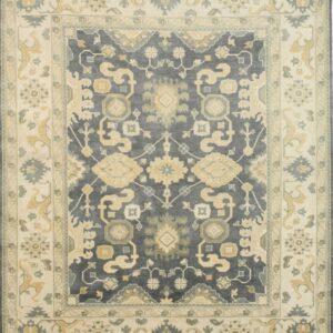 Traditional patterned rug with a deep gray center field and thick cream border detailed with gold motifs.