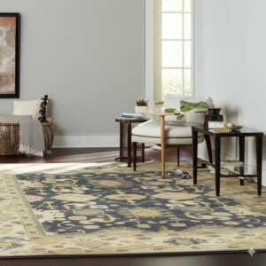 Ornate dark blue and beige rug defines a bright seating area with dark wood floors.