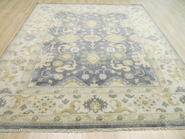 Traditional blue-gray rug with ivory and yellow geometric patterns lying on light wood planks.