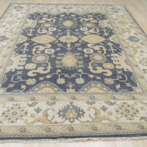 Navy blue and cream traditional area rug with gold and gray patterns on light wood flooring.