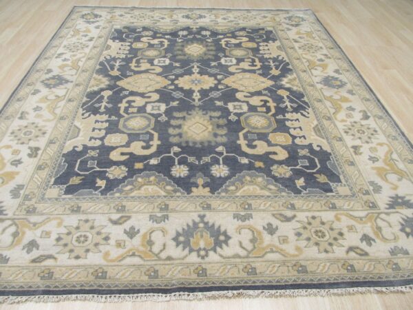 Navy blue and cream traditional area rug with gold and gray patterns on light wood flooring.