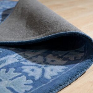 A textured blue patterned rug is curled up, revealing the gray backing and light wood floor.