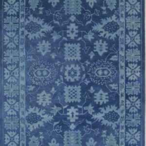 Deep indigo rug with a light blue plush pile and a faded traditional floral design and border.