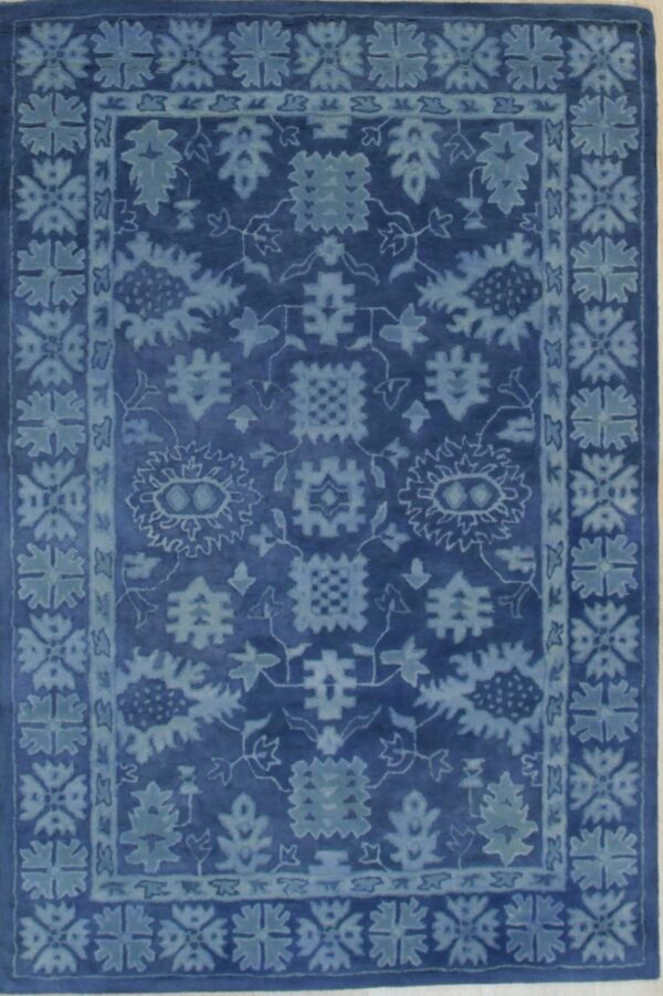 Deep indigo rug with a light blue plush pile and a faded traditional floral design and border.