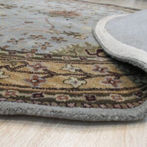 Traditional light blue and gold floral rug partially rolled back, showing its woven backing on light wood flooring.