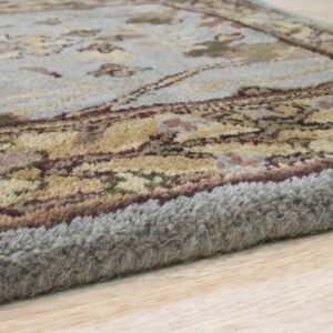 The thick, light gray edge and blue floral pattern of the rug are visible on light wood planks.