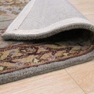 Plush blue and tan patterned rug rolled to reveal its backing on light hardwood flooring.