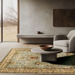 Ornate light blue and tan floral rug under a round gray coffee table and a textured modern armchair.