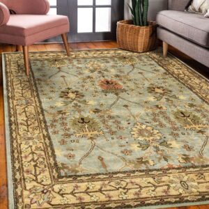 High-pile blue rug features a detailed floral pattern and tan border next to a pink armchair.