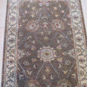 Dark brown and cream runner rug with a repeating floral trellis pattern, lying on light wood flooring.