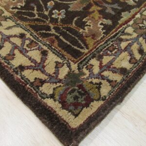 Textured, medium-pile rug with dark brown field and multicolored floral patterns rests on light hardwood.