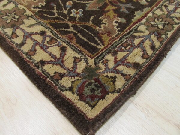 Textured, medium-pile rug with dark brown field and multicolored floral patterns rests on light hardwood.