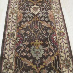 Dark brown traditional runner rug with multicolor floral motifs and a light beige border on wood plank flooring.