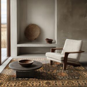 Dark floral rug with gold borders anchors a minimalist room with a textured cream armchair and large window.