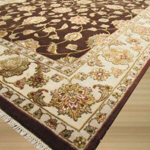 A plush floral rug in dark brown and cream tones rests on light blonde wood flooring.
