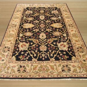 Navy blue and cream oriental rug featuring complex floral patterns displayed on light wood plank flooring.