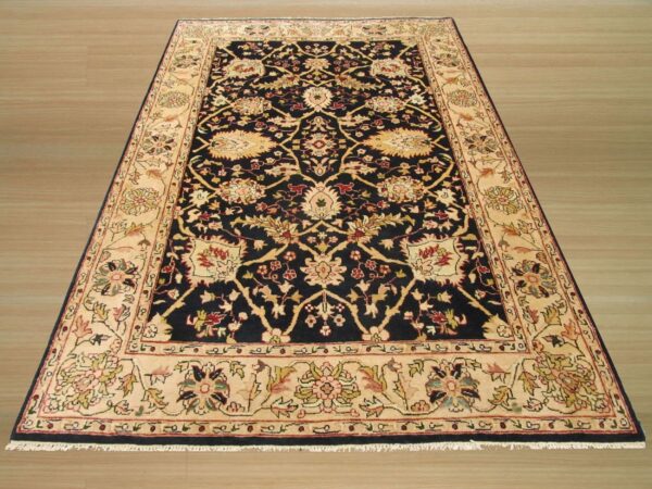 Navy blue and cream oriental rug featuring complex floral patterns displayed on light wood plank flooring.