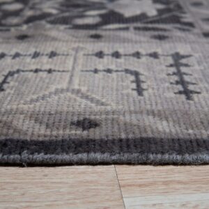 Low-angle view of a short-pile gray and charcoal patterned rug resting on light wood planks.