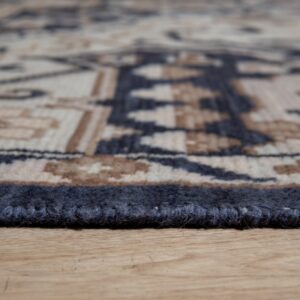 Textured dark blue rug binding and tribal pattern edge resting on light brown wood flooring.