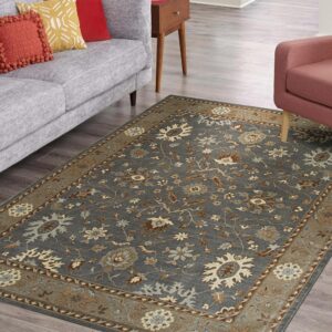 Gray-blue traditional floral rug anchors a gray sofa and pink chair on light wood planks.