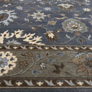 Traditional rug in slate blue featuring floral motifs in cream, light blue, and brown on wood flooring.