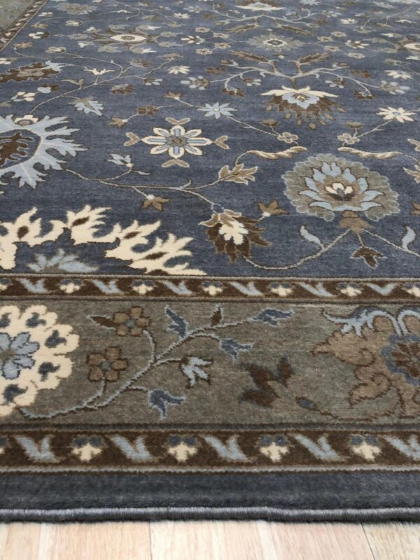 Traditional rug in slate blue featuring floral motifs in cream, light blue, and brown on wood flooring.