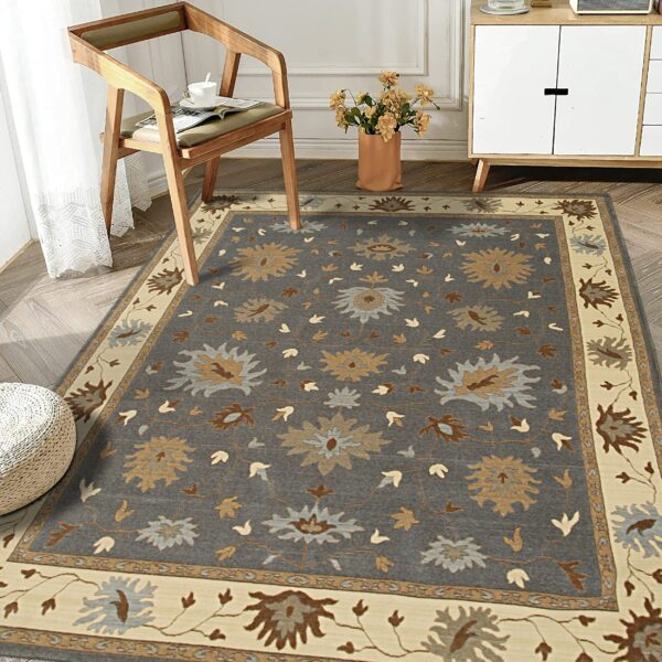 Dark gray floral rug featuring tan and light blue medallions and a wide cream border on wood flooring.