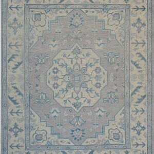 Low-pile rug featuring a central geometric medallion and borders in muted lilac, cream, and slate blue.