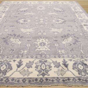 Pale gray and cream traditional rug features stylized floral motifs on light wood flooring.