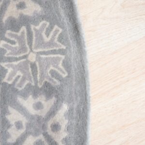 Close-up of a plush gray rug with an abstract beige geometric pattern on light wood flooring.