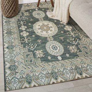 A low-pile teal and tan geometric rug anchors a room with light wood floors and beige upholstered furniture.