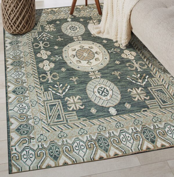 A low-pile teal and tan geometric rug anchors a room with light wood floors and beige upholstered furniture.