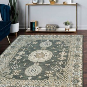 Low-pile green rug with light beige geometric patterns on dark wood floors near a blue chair.