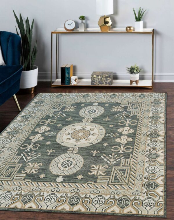 Low-pile green rug with light beige geometric patterns on dark wood floors near a blue chair.