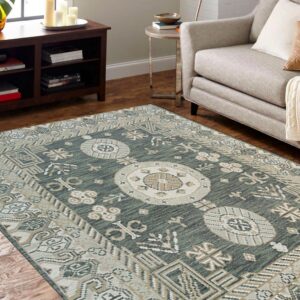 Teal and cream medallion rug on hardwood floors next to a gray upholstered sofa and dark brown cabinet.