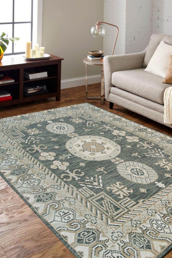 Teal and cream medallion rug on hardwood floors next to a gray upholstered sofa and dark brown cabinet.