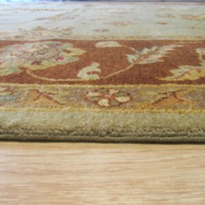 A medium-pile rug in sage and rust floral patterns rests on a light hardwood floor.