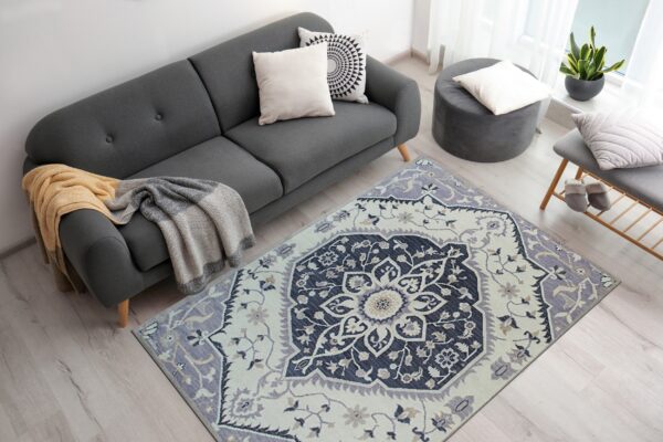 Navy and lavender traditional rug centering a gray sofa area on light wood flooring.