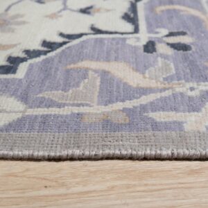 Traditional rug border featuring lavender, cream, and gray designs rests on light wood floors.