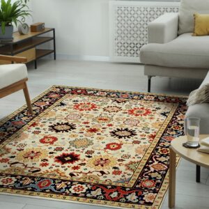 Cream and multicolored patterned rug placed on light wood floor between a sofa and armchair.