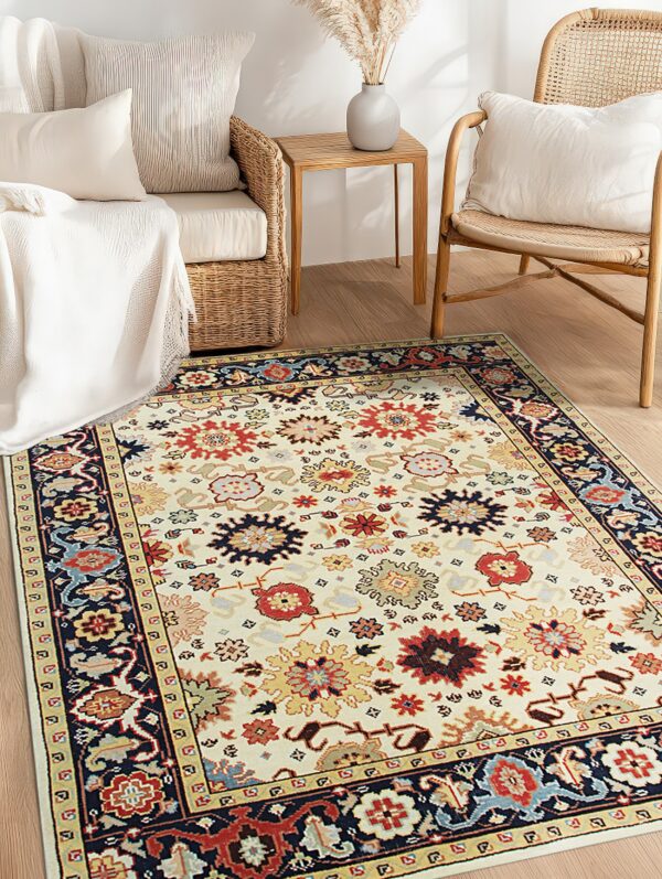 An ivory floral medallion rug with red and navy accents is centered on a wooden floor near wicker seating.