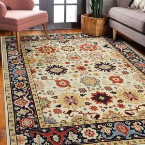 A cream rug featuring traditional multicolored floral medallions and a navy border sits on a wooden floor.