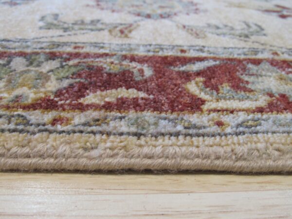Low-pile rug edge shows red and beige traditional patterns resting on light wood floorboards.
