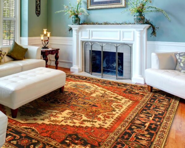 Ornate traditional rug in red, gold, and black centered between a white sofa and fireplace on a wood floor.